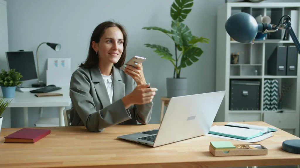 Femme d’affaires travaillant sur un ordinateur portable et un smartphone dans un bureau moderne pour gérer la facturation électronique.